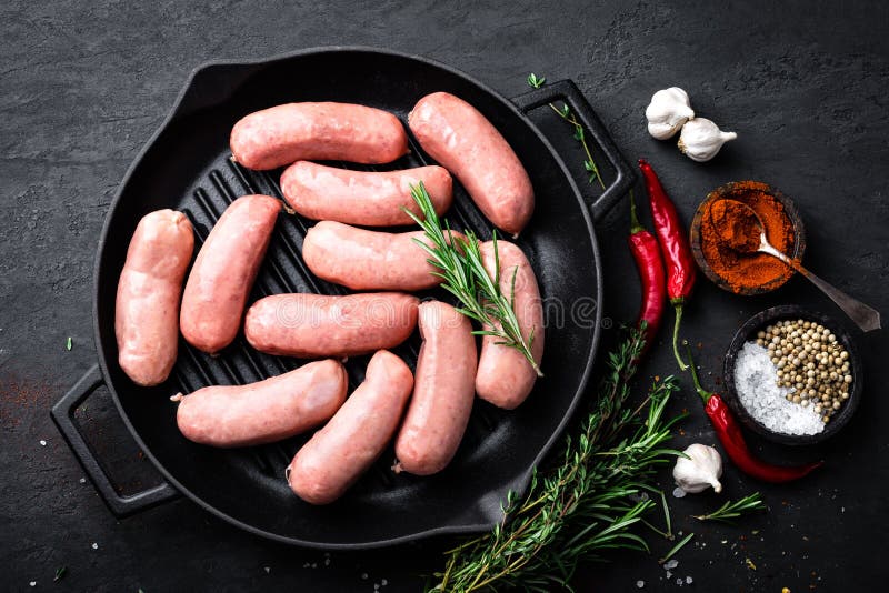 Fresh Raw Sausages on a Castiron Grill Pan on a Black Background Stock