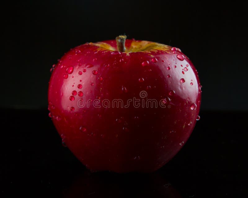 Fresh red apple with droplets of water agains black background. Fresh red apple with droplets of water agains black background