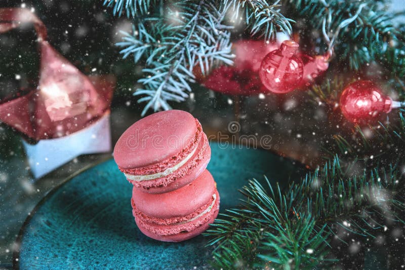 Fresh red macaroons at the Christmas table with the garland on the Christmas tree branches. Copy the place. Snow. The horizontal frame.