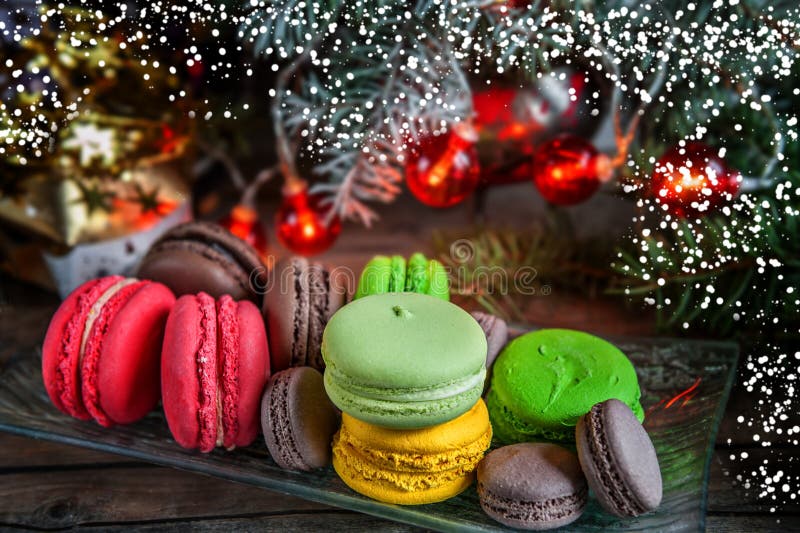 Fresh red macaroons at the Christmas table with the garland on the Christmas tree branches. Selective focus.. Snow. The horizontal frame.