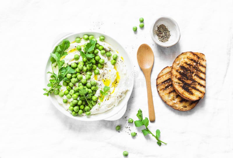 Fresh ricotta cheese with green peas, olive oil, pepper and herbs on a light background, top view. Healthy diet food - delicious b royalty free stock images Fresh ricotta cheese with green peas, olive oil, pepper and herbs on a light background, top view. Healthy diet food - delicious b royalty free stock images