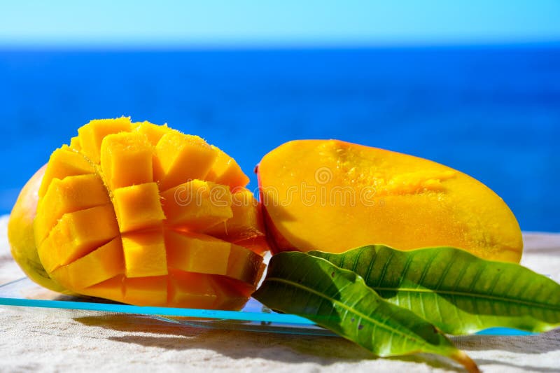 Fresh ripe sweet yellow mango fruit served on glass plate with blue seaview background royalty free stock photography Fresh ripe sweet yellow mango fruit served on glass plate with blue seaview background royalty free stock photography