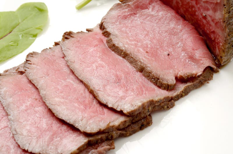 Fresh Roasted Beef on White Plate with Herbs in Restaurant Stock Photo