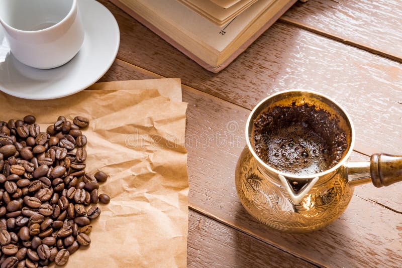 Fresh roasted coffe beans in cezve traditional turkish coffee pot opened book and cup on wooden table royalty free stock image Fresh roasted coffe beans in cezve traditional turkish coffee pot opened book and cup on wooden table royalty free stock image