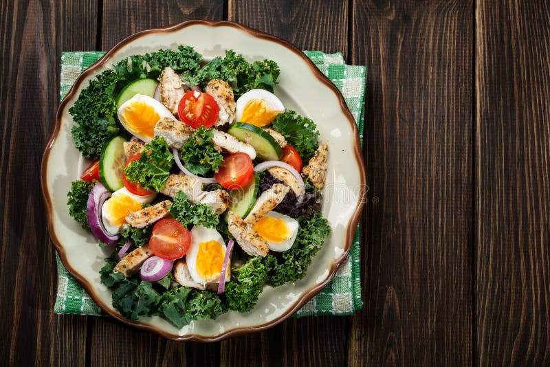 Fresh salad with chicken, tomatoes, eggs and lettuce on plate