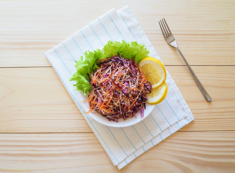 Fresh salad plate with mixed roots celery, carrot, red cabbage on light wooden background close up. Healthy food. Green meal.