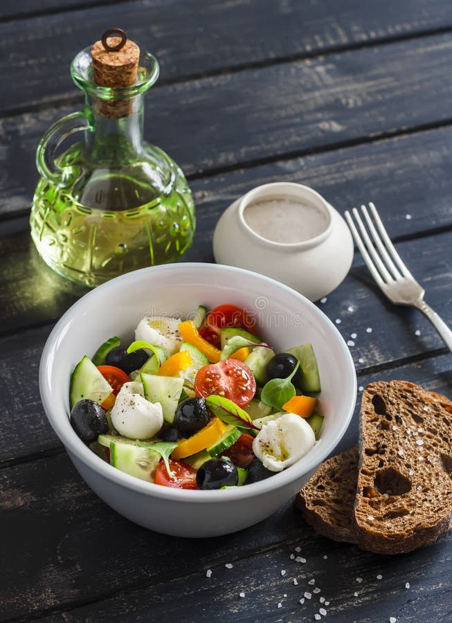 Fresh salad with tomatoes, cucumbers, peppers, olives and cheese in a ceramic bowl