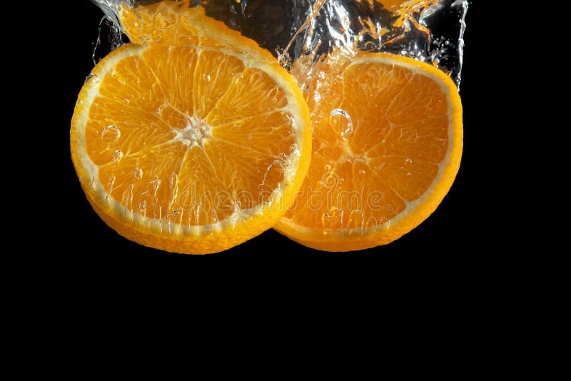 Fresh sliced orange fruit in water splash isolated on black background. Minimal food concept