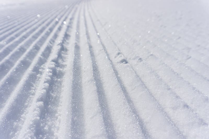 Fresh snow groomer tracks on a mountain ski piste, background. Fresh snow groomer tracks on a mountain ski piste, background