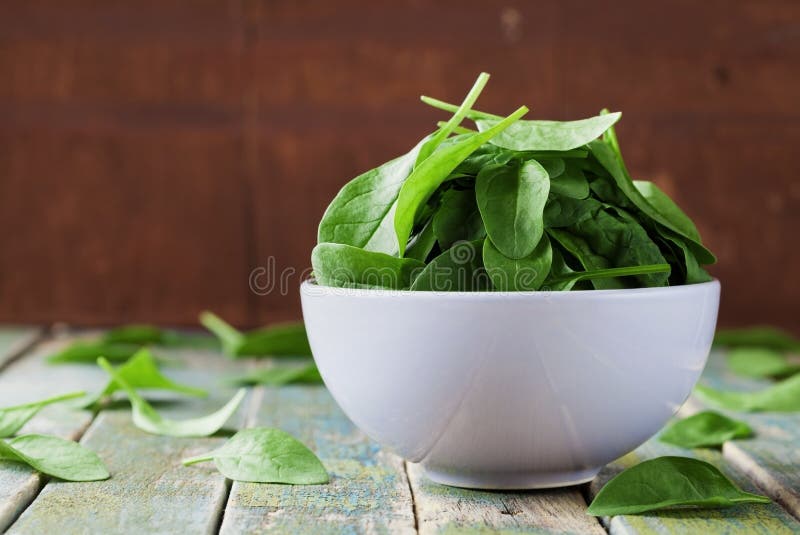 Fresh Spinach Leaves in Bowl on Rustic Kitchen Table Stock Image