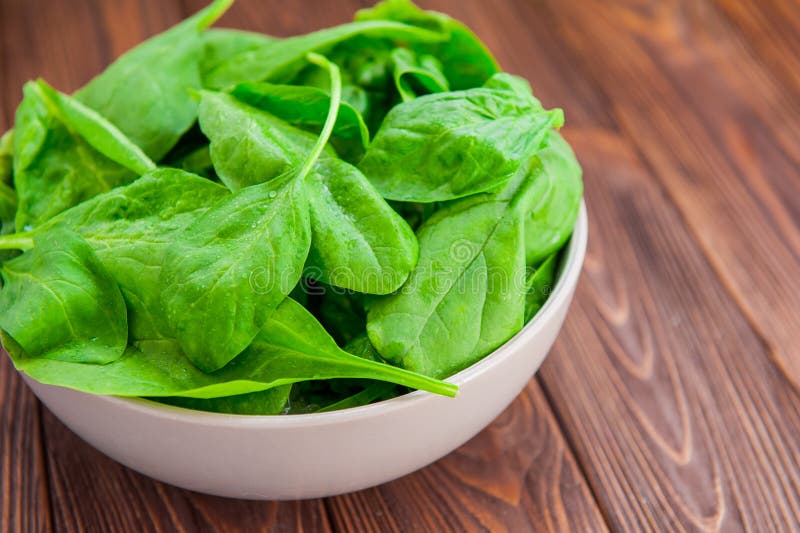 Fresh Spinach Leaves with Water Drops in Ceramic Bowl on the Dark Rustic Wooden Background