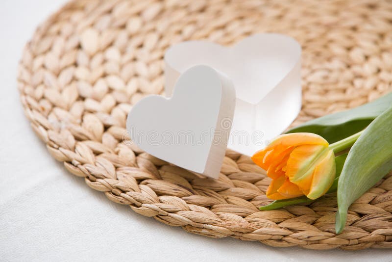 A fresh spring orange tulip and two cute heart symbols on the straw board. Home romantic royalty free stock photo A fresh spring orange tulip and two cute heart symbols on the straw board. Home romantic royalty free stock photo