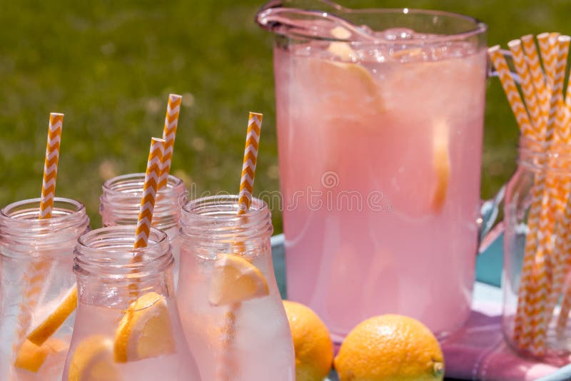 Close Up Of Picnic Party In The Park Drink Table With Large Pitcher And  Glass Bottles Filled With Ice Cold Pink Lemonade And Fresh Lemons, With  Yellow Swirled Straws And Signs Sitting