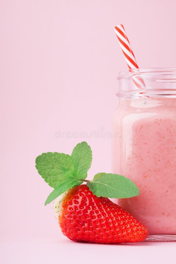 Fresh strawberry smoothie or milkshake in mason jar decorated mint on pink pastel background. Healthy food for breakfast and snack royalty free stock photography Fresh strawberry smoothie or milkshake in mason jar decorated mint on pink pastel background. Healthy food for breakfast and snack royalty free stock photography