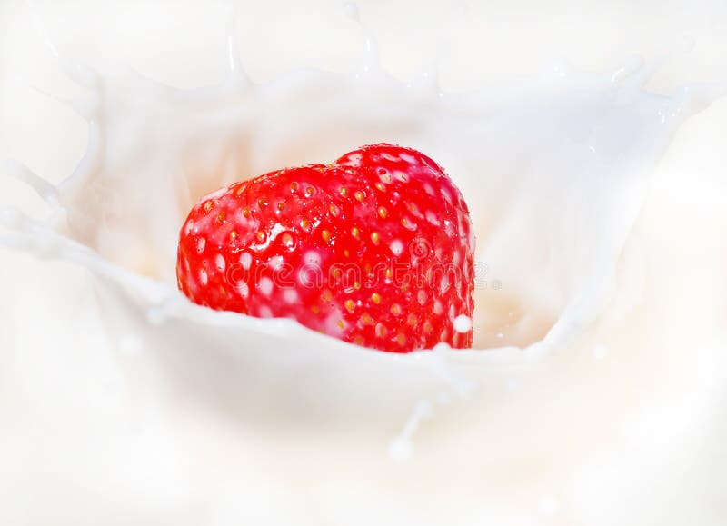 Fresh strawberry splashing into milk or yogurt