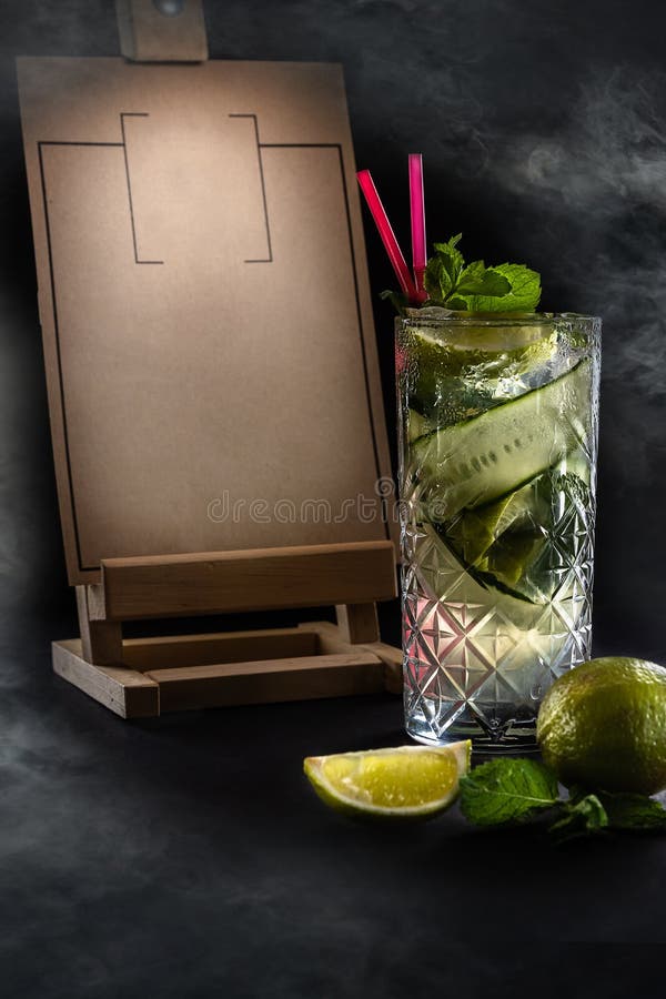 Fresh summer cucumber lemonade with two pink straws in the glass. Wooden Menu Holder with copy space on the black background with stock photos Fresh summer cucumber lemonade with two pink straws in the glass. Wooden Menu Holder with copy space on the black background with stock photos