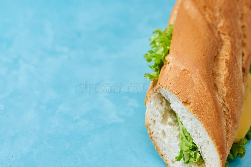 Fresh and tasty sandwich with cheese and vegetables on cutting board over blue background, selective focus. royalty free stock photo Fresh and tasty sandwich with cheese and vegetables on cutting board over blue background, selective focus. royalty free stock photo