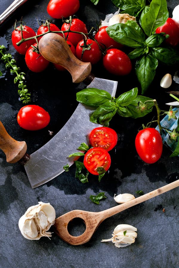 Fresh tomatoes with basil garlic and sea salt on black slate background stock photos Fresh tomatoes with basil garlic and sea salt on black slate background stock photos