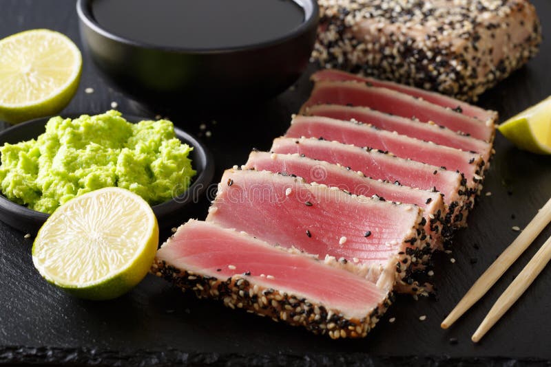 Fresh tuna meat in sesame and soy sauce, wasabi, lime closeup. h