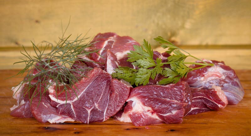 Fresh uncooked beef meat slices over wooden cutting board ready