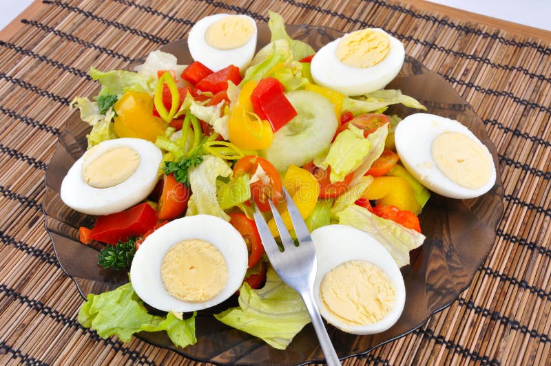 Fresh vegetable salad with eggs and fork on bamboo background