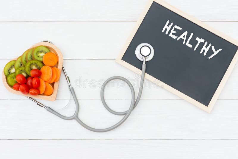 Fresh vegetable salad and healthy food on the shape heart with medical stethoscope for diet and weight loss on the old white wooden. Healthy Concept.