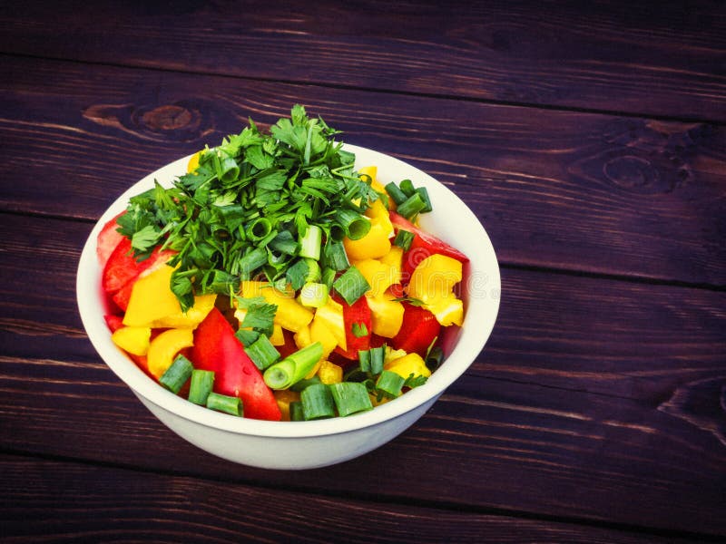 Fresh vegetable salad with herbs in a white bowl on a dark wooden table stock photo Fresh vegetable salad with herbs in a white bowl on a dark wooden table stock photo