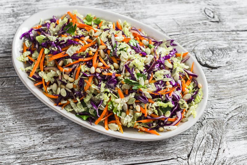 Fresh vegetable salad with red cabbage, carrots, sweet peppers, herbs and seeds. Healthy vegetarian food. On light wooden rustic background