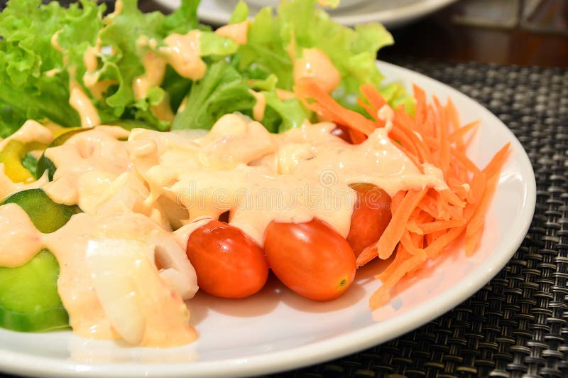 Fresh vegetable salad in white plate topped with thousand island dressing