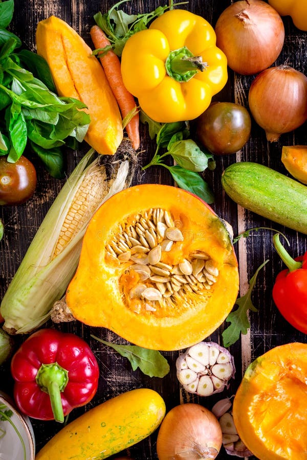 Fresh vegetables scaterred on a rustic dark textured table. Autumn background