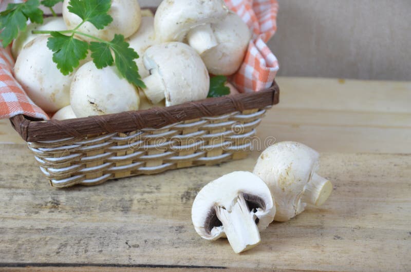 Fresh white mushrooms champignon in brown basket on wooden background. Top view. Copy space royalty free stock photo Fresh white mushrooms champignon in brown basket on wooden background. Top view. Copy space royalty free stock photo