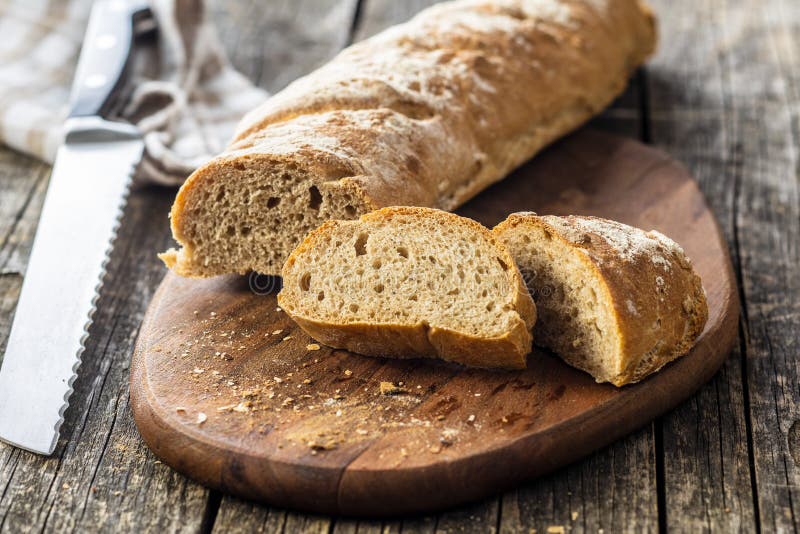 Fresh whole grain bread baguette. Sliced fresh whole grain bread baguette on cutting board