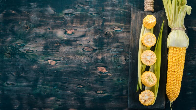 Fresh yellow corn on a black wooden table. Vegetables.