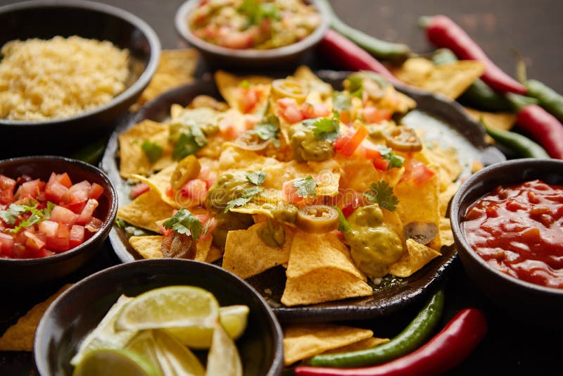 Yellow Nacho in White Bowl on the Wooden Table with Tomato Next To it