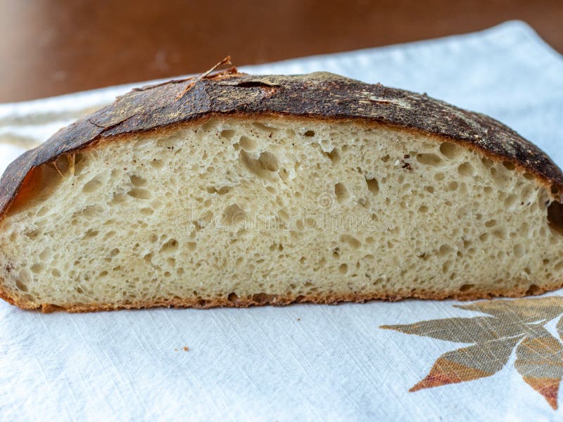 Freshly baked artisan loaf of bread cut to show crumb texture and crusty exterior, resting on a fall themed placemat stock photo Freshly baked artisan loaf of bread cut to show crumb texture and crusty exterior, resting on a fall themed placemat stock photo
