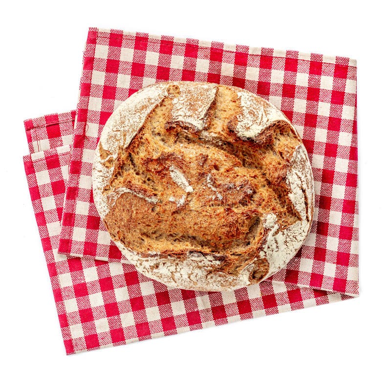 Freshly baked bread on red checkered napkin isolated on white background. Rustic wholegrain bread, round shape. Top view