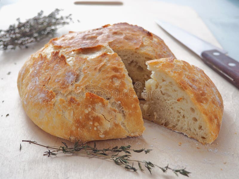 Freshly baked bread with thyme sprig upon cutting board. One piece is cut. stock photography Freshly baked bread with thyme sprig upon cutting board. One piece is cut. stock photography