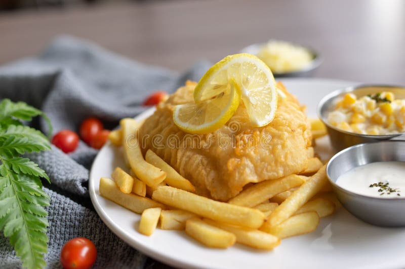 A Fish and Chips Meal Served on a Plate with Dipping Sauces Stock Photo