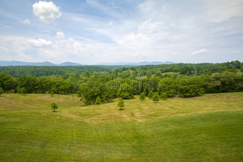 Freshly mowed field with forst and distant mountains in background under bright blue sky royalty free stock images Freshly mowed field with forst and distant mountains in background under bright blue sky royalty free stock images