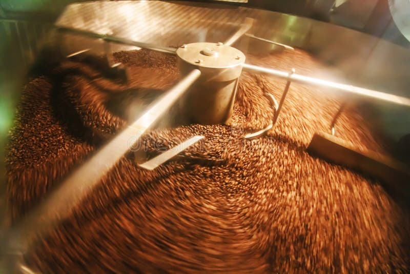 The freshly roasted coffee beans from a coffee roaster being poured into the cooling cylinder. Frozen moment. The freshly roasted coffee beans from a coffee roaster being poured into the cooling cylinder. Frozen moment.