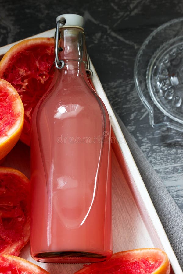 Freshly Squeezed Grapefruit Juice in a Glass Bottle, a Juicer and Fruit