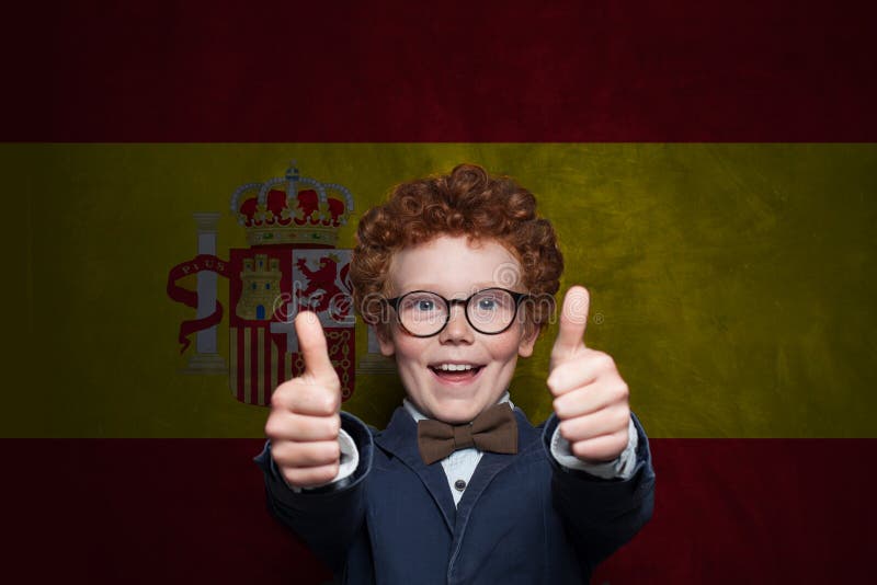 Freudender Junge in Schuluniform auf spanischer Flagge. Konzept Bildung und Kindheit in Spanien lizenzfreie stockfotos