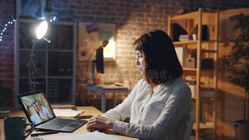 Freuen Sie sich auf freudliches Skype im Büro, das mit Freunden mit einem Laptop mit der Hand chattet