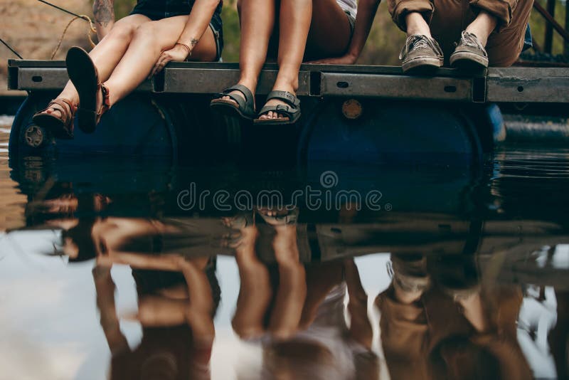 Freunde, die auf einem Schwimmdock auf einem See sitzen lizenzfreie stockbilder Freunde, die auf einem Schwimmdock auf einem See sitzen lizenzfreie stockbilder