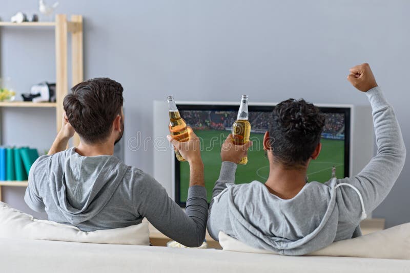 Freunde, die Fußball in Fernsehen genießen lizenzfreie stockfotos Freunde, die Fußball in Fernsehen genießen lizenzfreie stockfotos