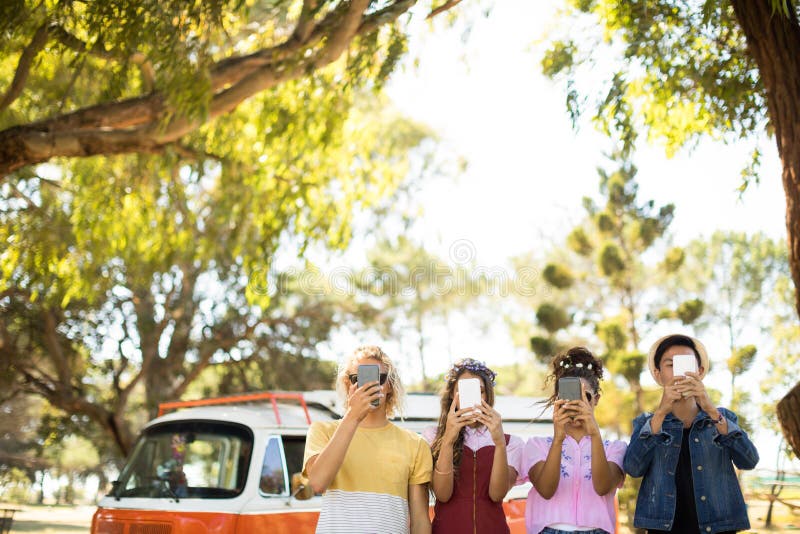 Freunde, die intelligentes Telefon vor Gesicht halten stockfotos Freunde, die intelligentes Telefon vor Gesicht halten stockfotos