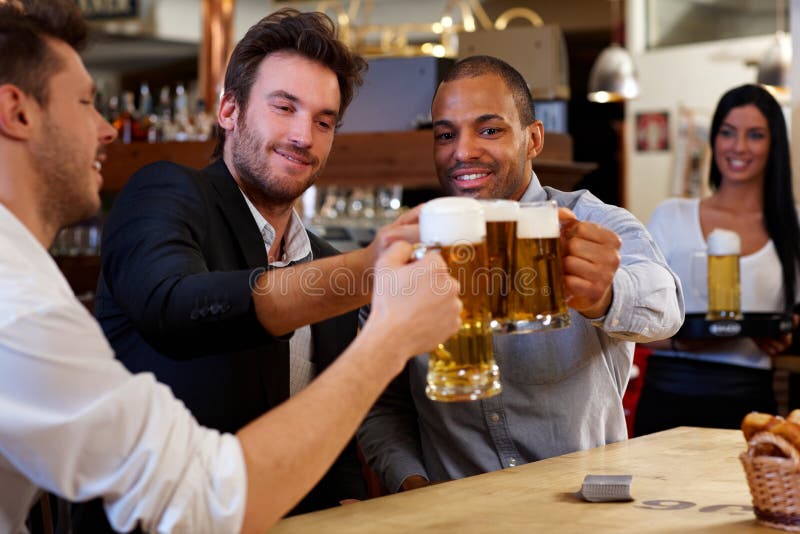 Freunde, die mit den Bierkrügen in der Kneipe klirren lizenzfreie stockfotos Freunde, die mit den Bierkrügen in der Kneipe klirren lizenzfreie stockfotos
