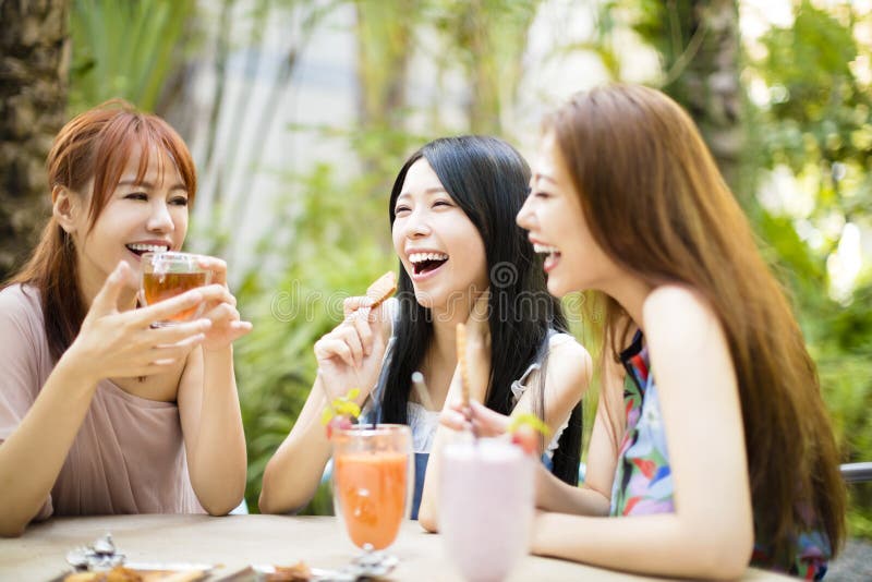 Freundinnen, die im Restaurantgarten sprechen stockfotografie Freundinnen, die im Restaurantgarten sprechen stockfotografie