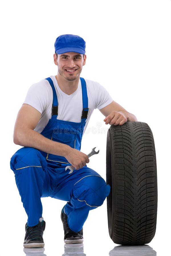 Freundlicher Automechaniker mit Reifen stockfotografie Freundlicher Automechaniker mit Reifen stockfotografie