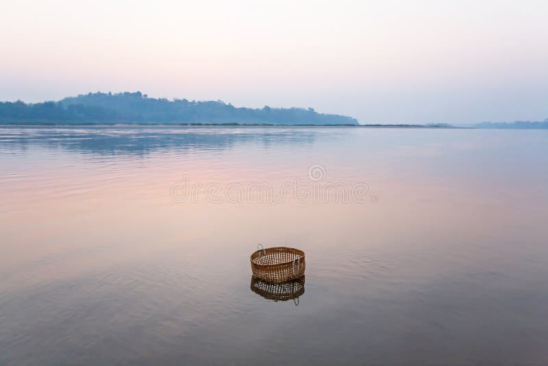 Fridsamt fridfullt vid floden, en bambukorg doppar i Mekonget River på vintermorgonen, stilleben i lantliga Laos arkivfoto Fridsamt fridfullt vid floden, en bambukorg doppar i Mekonget River på vintermorgonen, stilleben i lantliga Laos arkivfoto